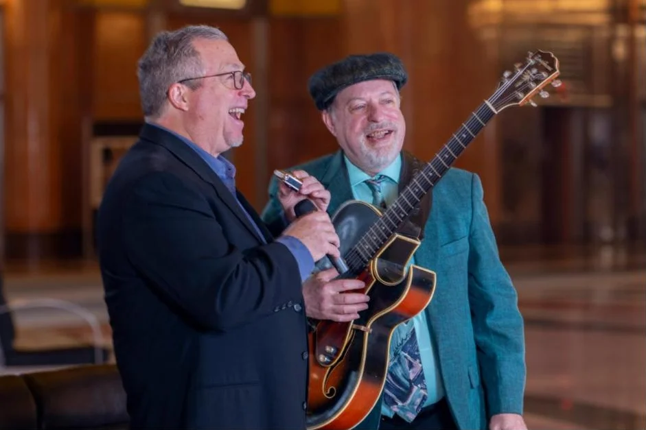 Greg Chako sharing a laugh with a singer while playing guitar